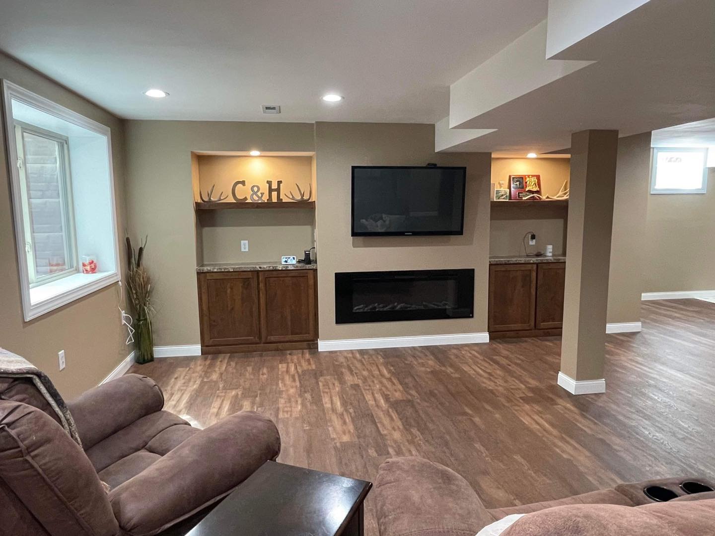 Basement fireplace and television wall with wood cabinets and illuminated display shelves