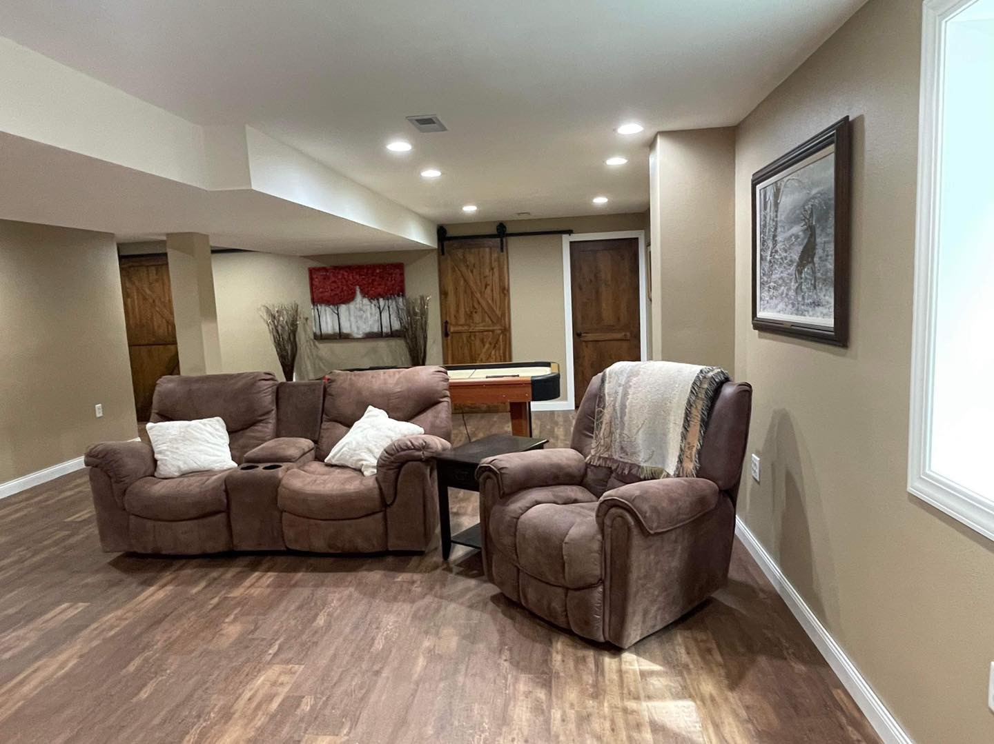 Basement seating area with recessed lighting, wood doors, and wood-look flooring