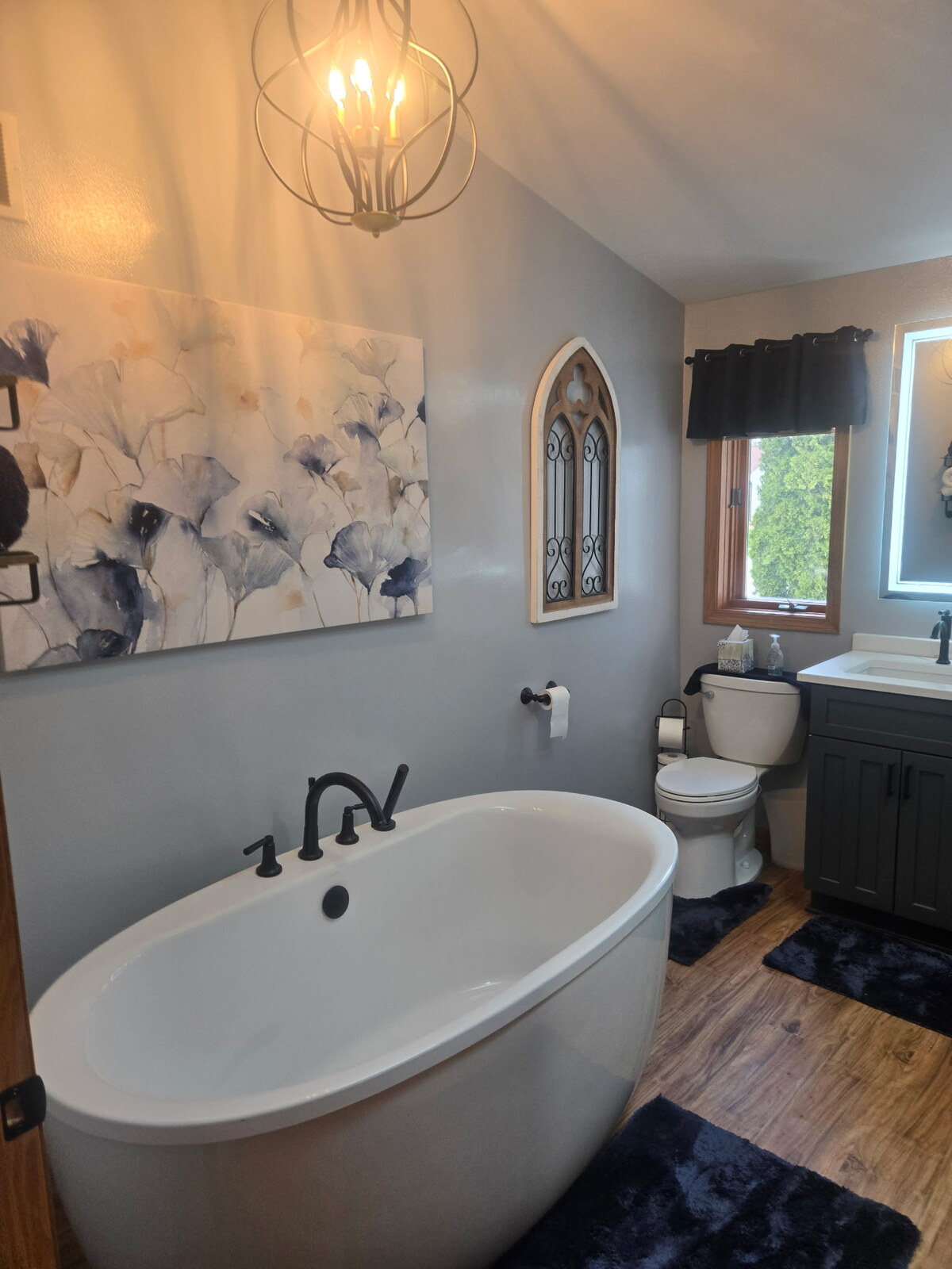 Completed bathroom with freestanding tub, dark vanity, and new flooring