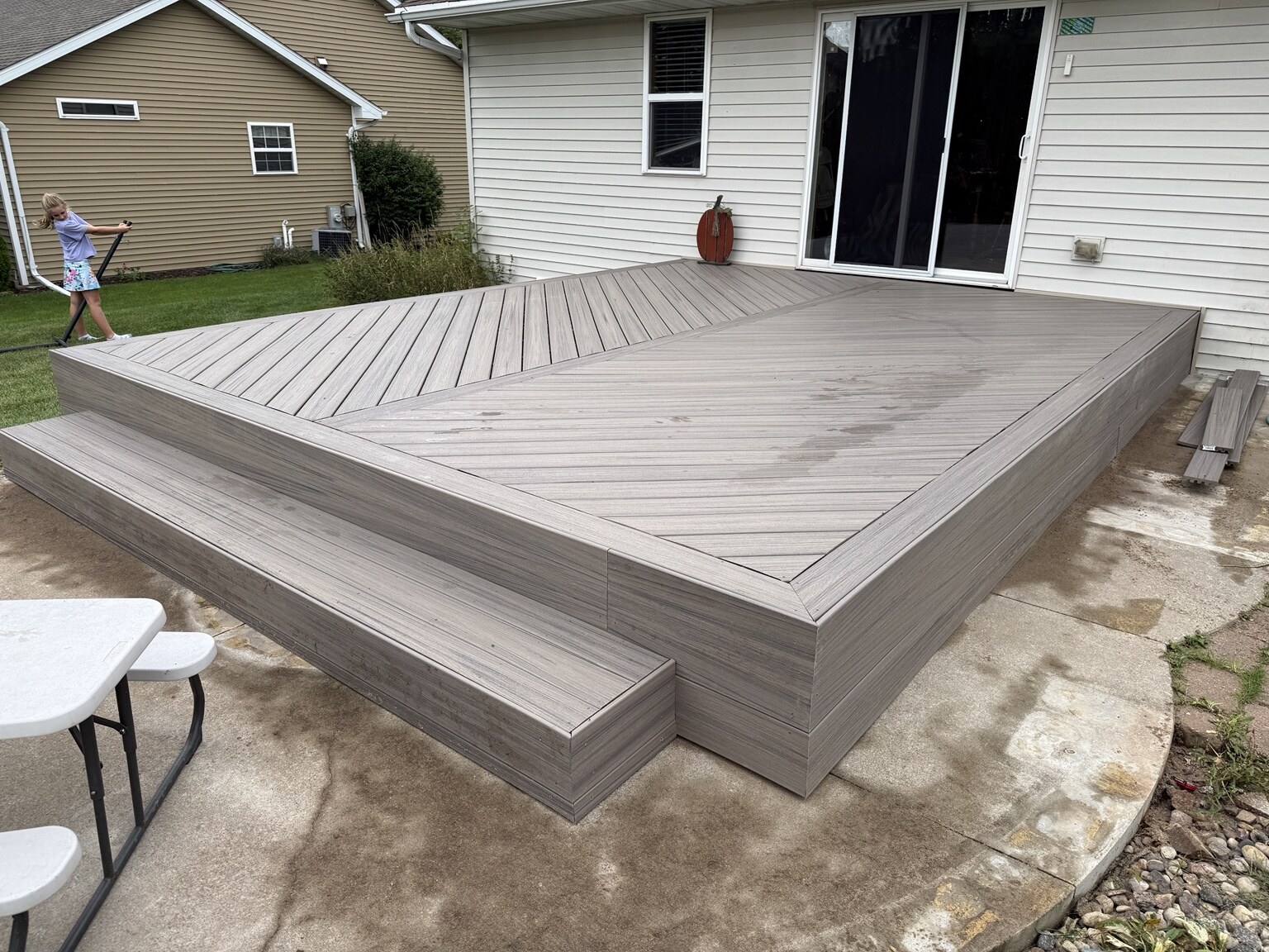 Completed gray composite deck with diagonal layout, wrapped fascia, and steps