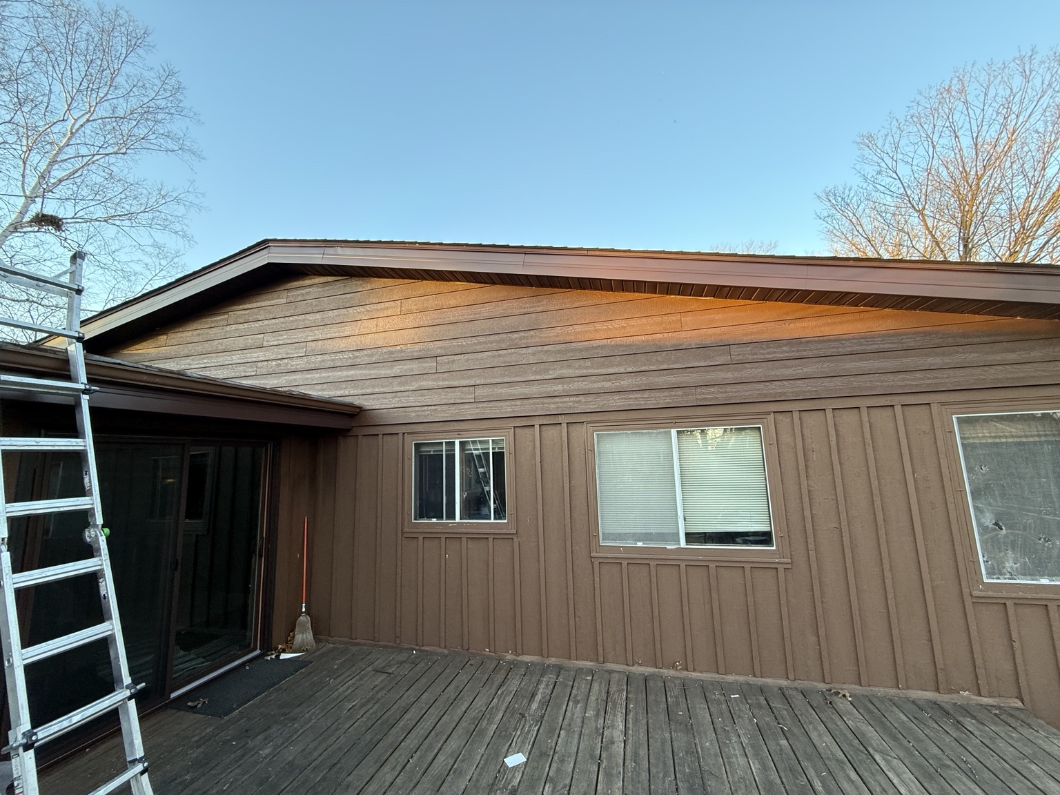 Home exterior with vertical siding, horizontal gable siding, windows, and a wood deck