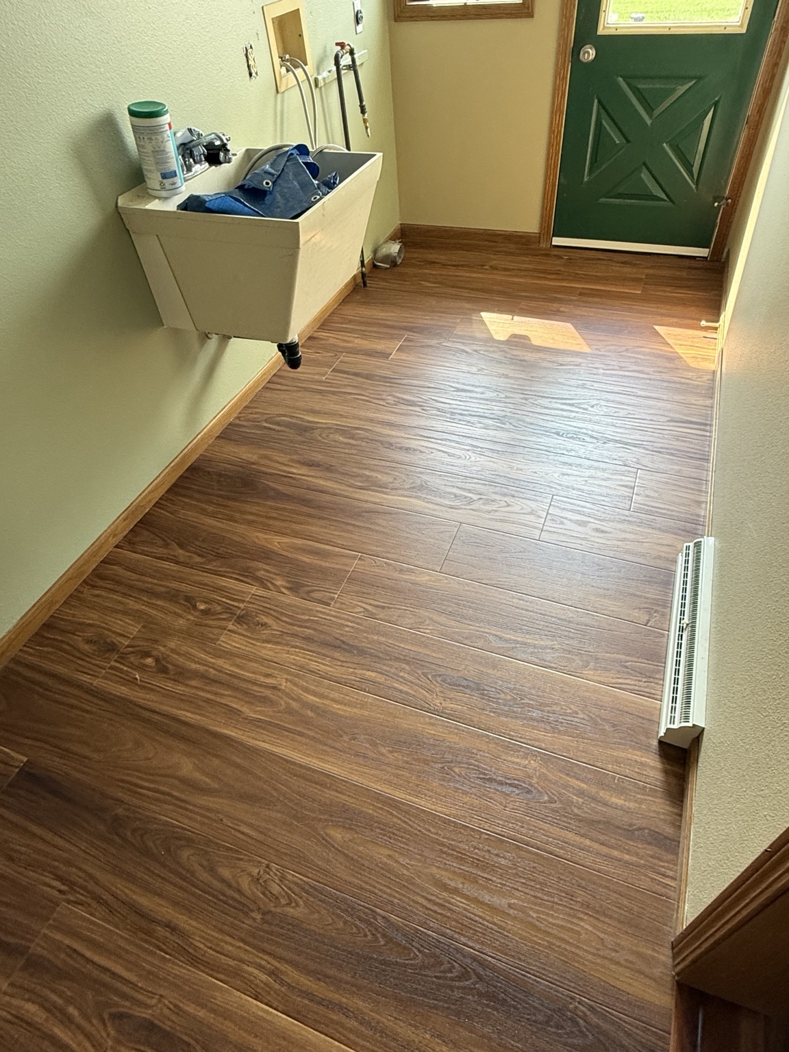 Entry hall with warm wood-look flooring, wood baseboards, and a green exterior door