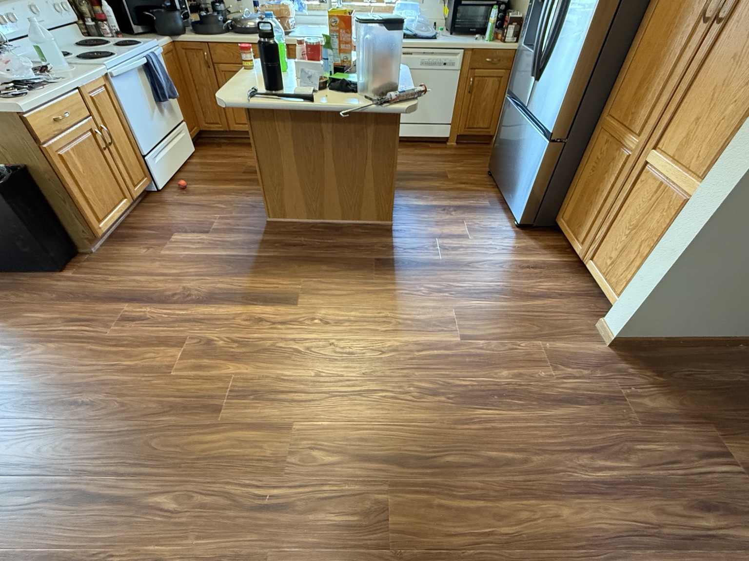 Kitchen with warm wood-look flooring, wood cabinetry, and a central island