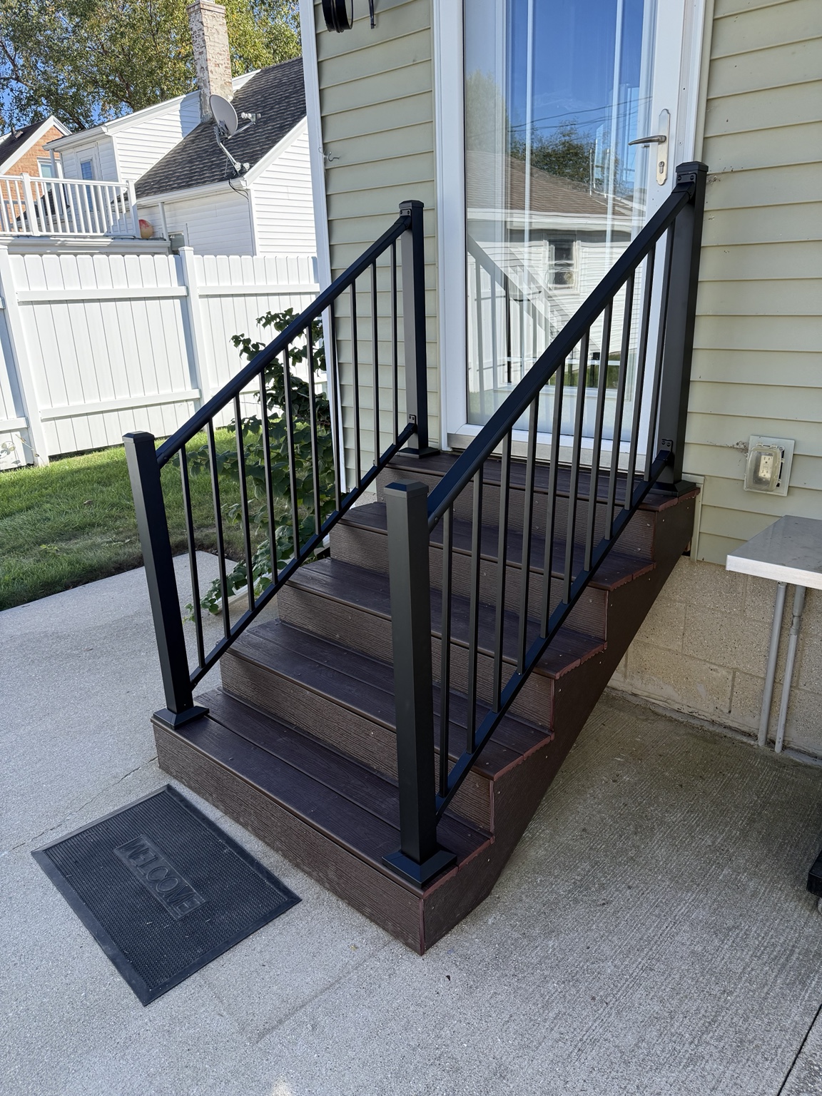 Dark deck steps with black metal railings at a side entrance