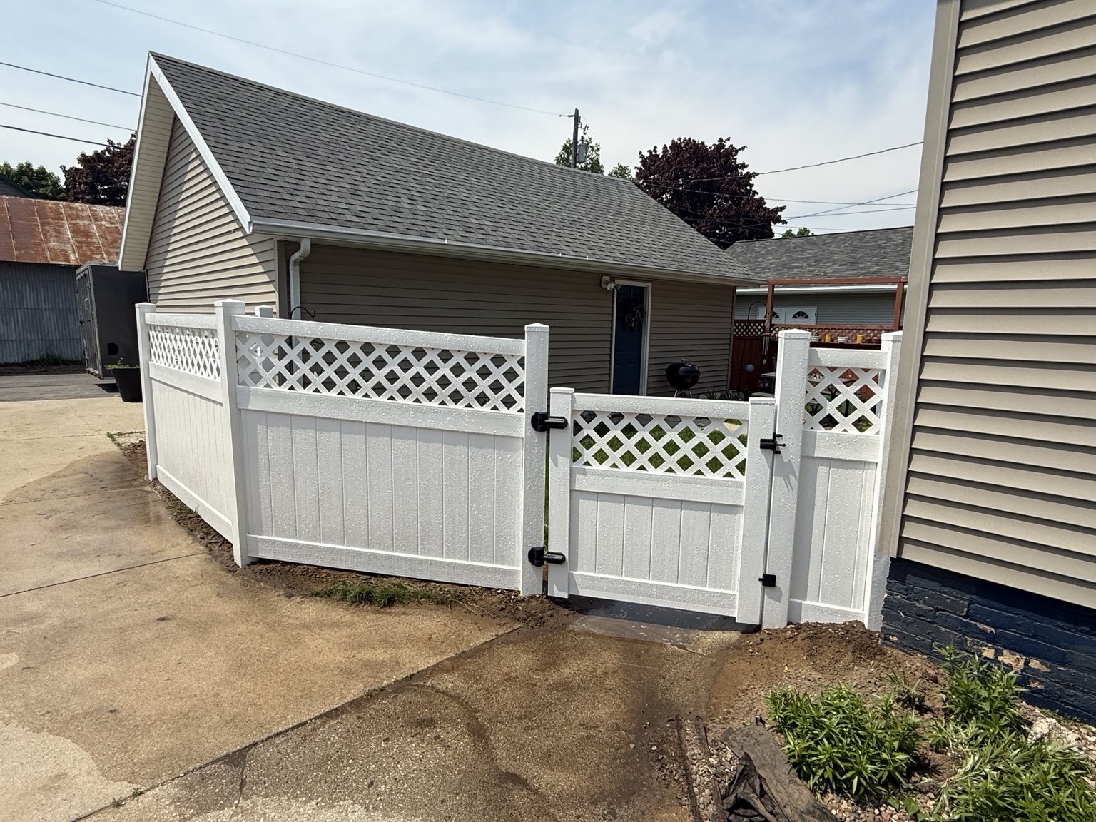 White vinyl fence with lattice top and a matching gate beside a garage