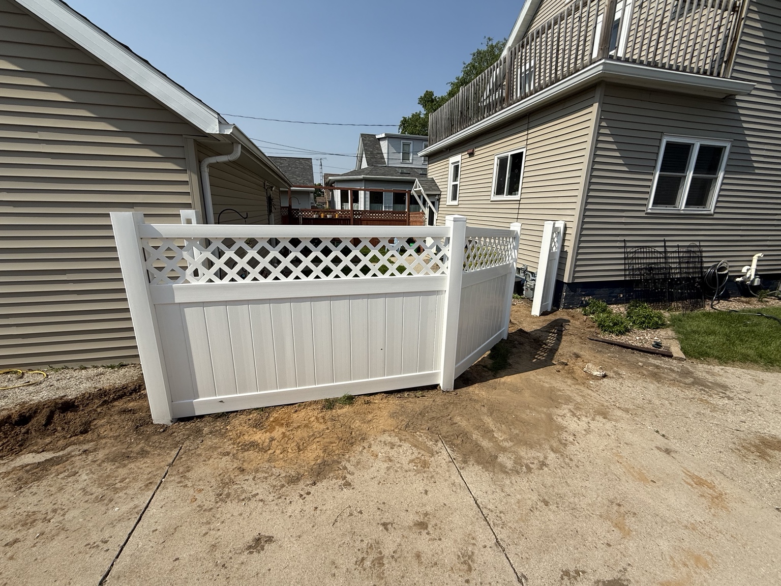 White vinyl lattice-top fence corner beside a home