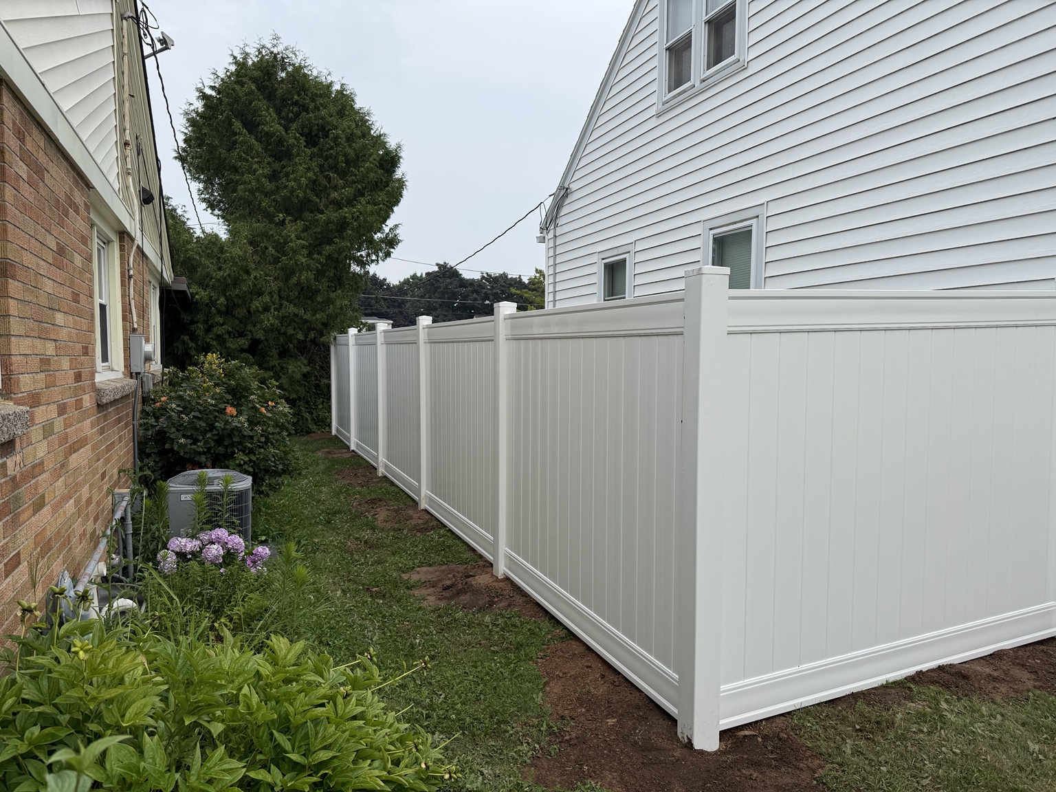 White vinyl privacy fence along a side yard between homes